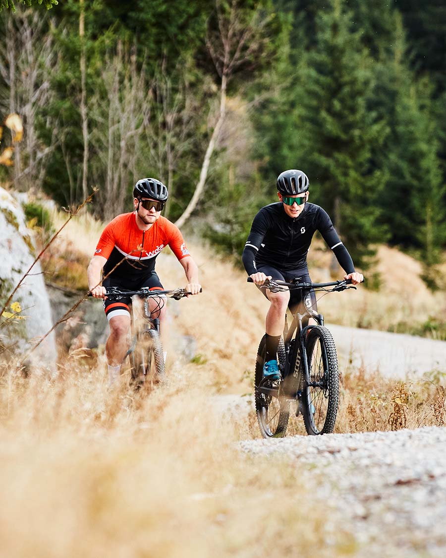 Zwei Mountainbiker auf einem hügeligem Kiesweg