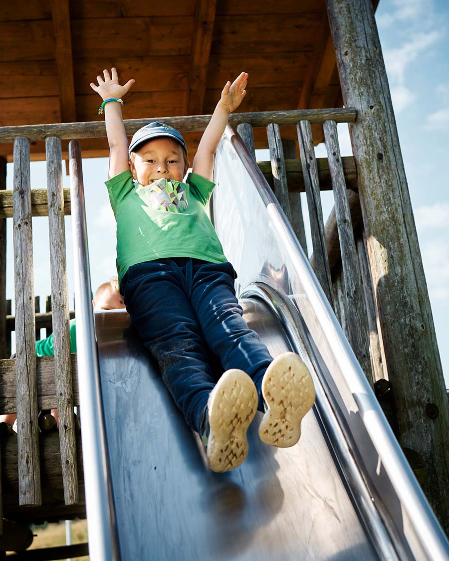 Junge auf einer Rutsche am Spielplatz
