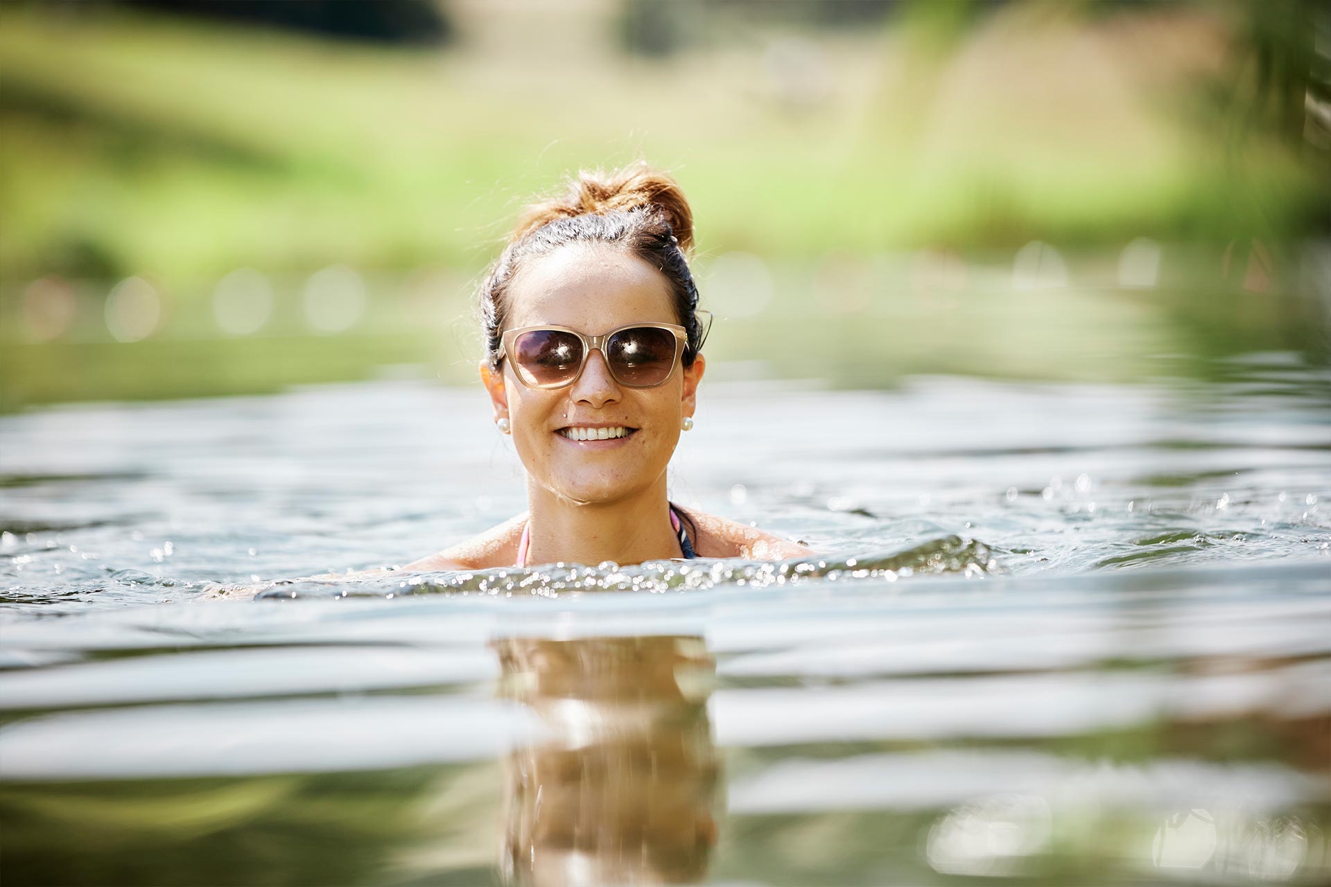 Frau schwimmt im kristallklaren Badesee