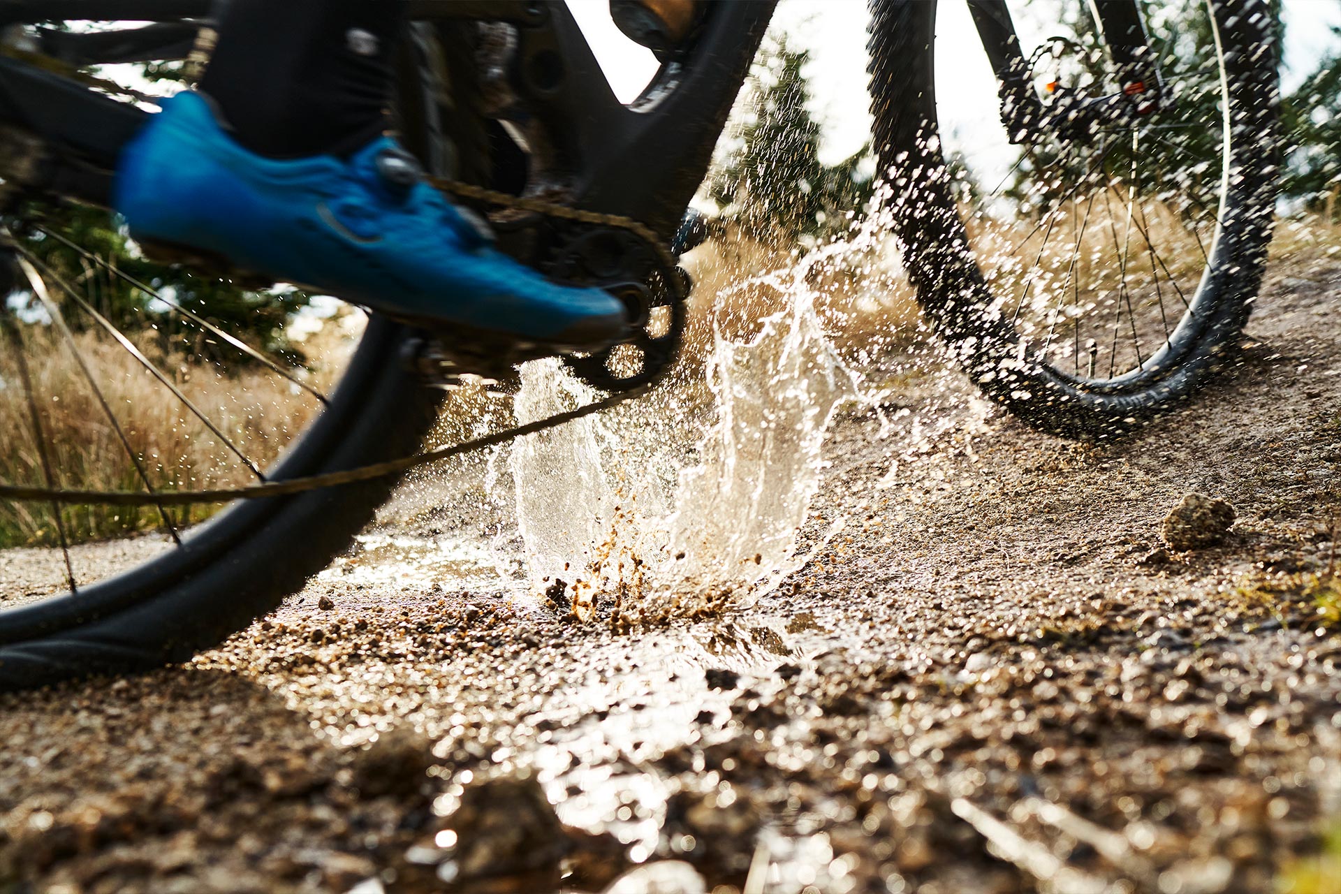 Nahaufnahme eines Mountainbiker der durch eine Pfütze fährt