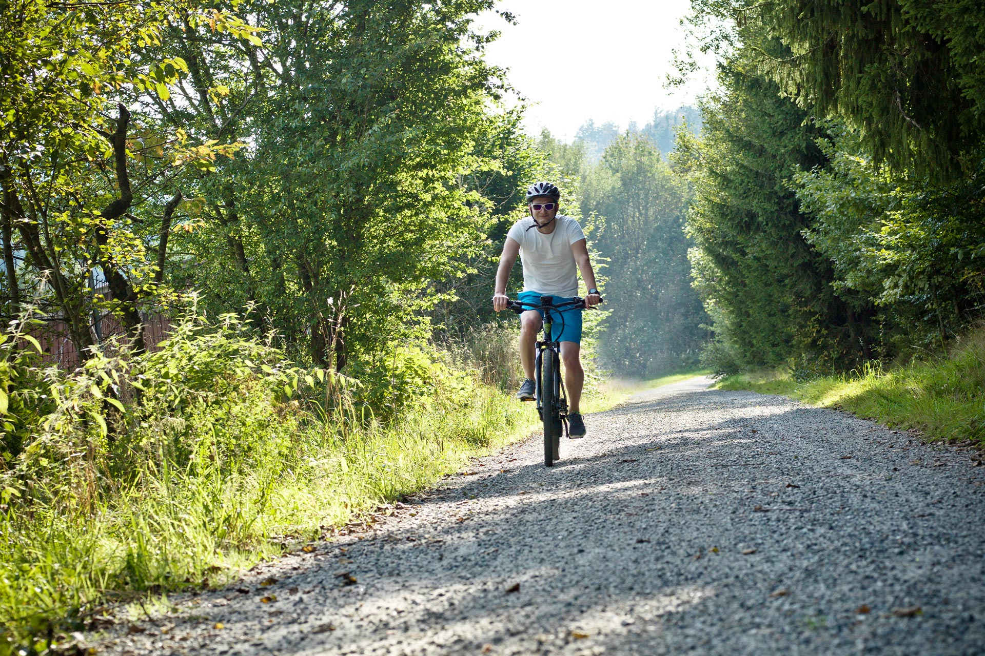 Radfahrer auf Kiesstraße mitten im Wald
